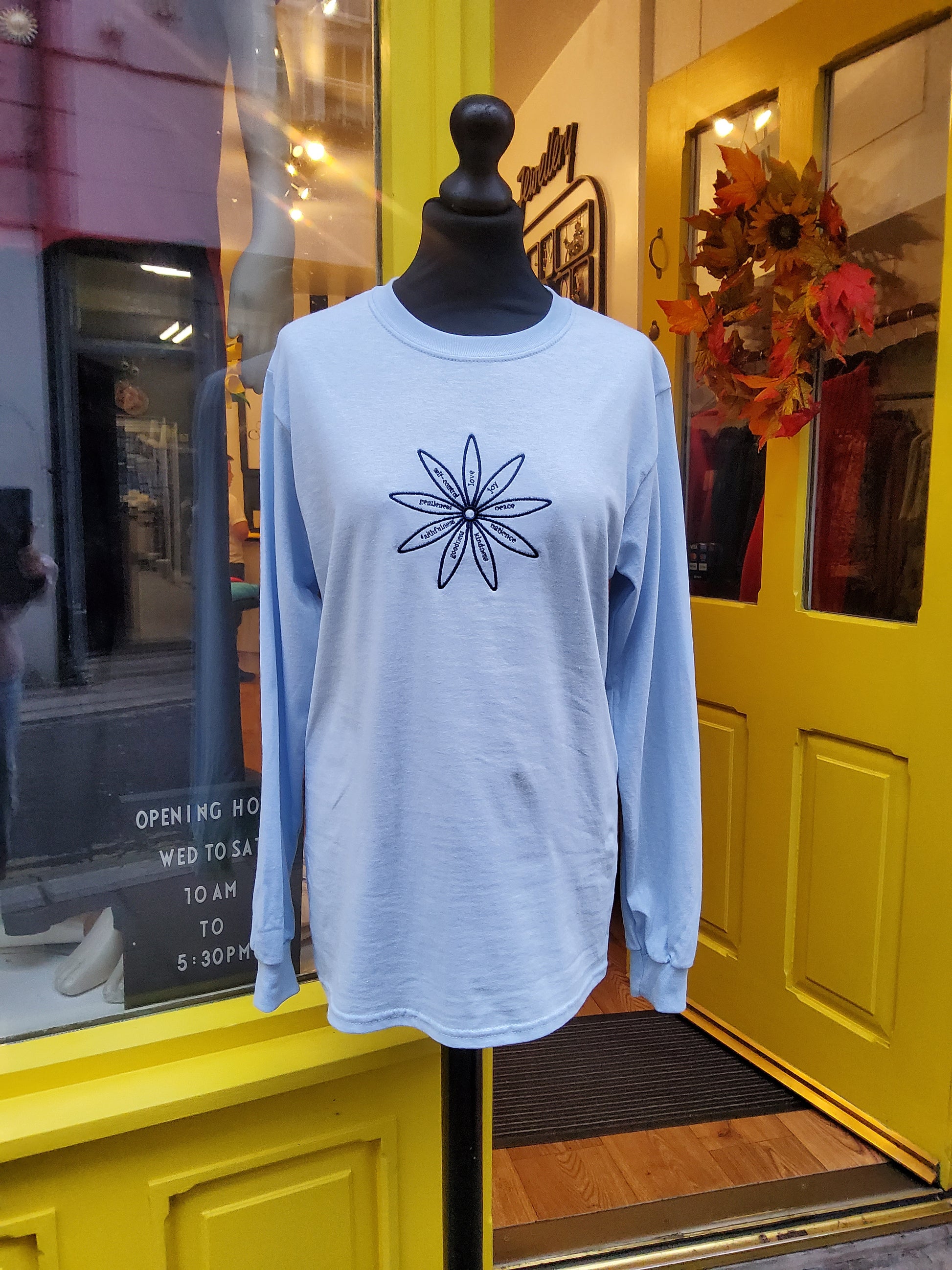 Light blue long sleeve top with embroidered flower design detailing the fruits of the Spirit 